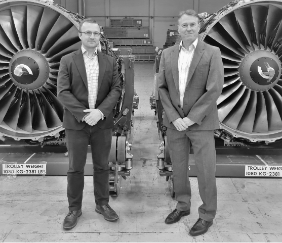 Aerfin staff standing in front of airplane engines in their HQ