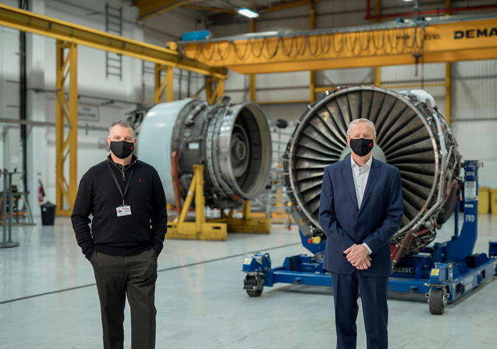 Aerfin staff standing in front of engines in AerFin facility.png